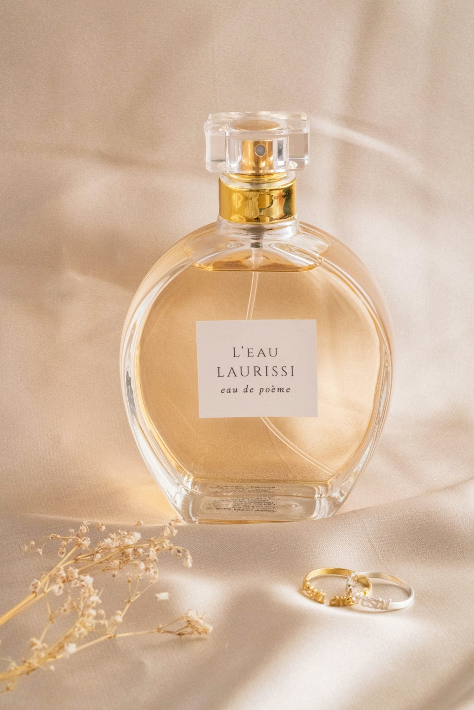 Clear glass perfume bottle with golden cap on beige satin.