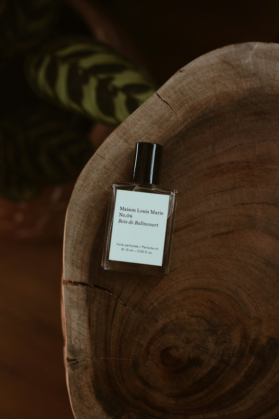Perfume oil bottle sits on a dark wooden surface.